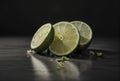 Fresh lime is cut into large slices on gray glass surface with mirror effect. Composition is on dark gradient background. Royalty Free Stock Photo