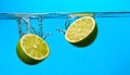 Fresh lime falling into water on blue background Royalty Free Stock Photo