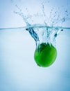 Fresh lime falling into water, on white Royalty Free Stock Photo