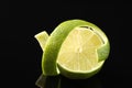 Fresh lime peel and half of fruit on black glass surface, closeup Royalty Free Stock Photo