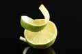 Fresh lime peel and half of fruit on black glass surface, closeup Royalty Free Stock Photo