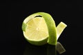 Fresh lime peel and half of fruit on black glass surface, closeup Royalty Free Stock Photo