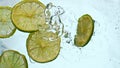 Fresh lime slices falling water close up. Juicy pieces acidic citrus floating. Royalty Free Stock Photo