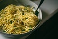 Fresh linguine in a bowl with garlic, olive oil and fresh basil. Pasta aglio e olio with nest of noodles on a fork. Room for copy.