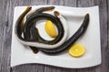 Fresh live fish lamprey on porcelain plate with lemon. Royalty Free Stock Photo