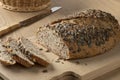 Fresh loaf and slices of spelt bread and a variety of seeds close up on a cutting board