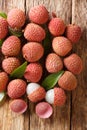 Fresh lychee and peeled showing the red skin and white flesh with green leaf. Vertical top view Royalty Free Stock Photo