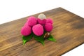 Fresh lychee and peeled showing the red skin and white flesh with green leaf on a wooden background. Lychi with leaves - tropical