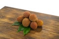 Fresh lychee and peeled showing the red skin and white flesh with green leaf on a wooden background. Lychi with leaves - tropical
