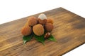 Fresh lychee and peeled showing the red skin and white flesh with green leaf on a wooden background. Lychi with leaves - tropical