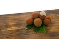 Fresh lychee and peeled showing the red skin and white flesh with green leaf on a wooden background. Lychi with leaves - tropical