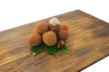 Fresh lychee and peeled showing the red skin and white flesh with green leaf on a wooden background. Lychi with leaves - tropical