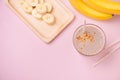 Fresh made banana smoothie in a glass on pink background Royalty Free Stock Photo