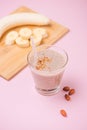 Fresh made banana smoothie in a glass on pink background Royalty Free Stock Photo