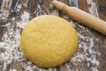 Fresh made dough next to a classic wood rolling pin