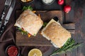 Fresh made Snack Sandwich with Fish Sticks, on wooden cutting board, on old dark  wooden table background, top view flat lay Royalty Free Stock Photo