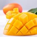 Fresh mango,beautiful chopped fruit with green leaves on bright wooden table background. Tropical fruit design concept, close up, Royalty Free Stock Photo