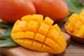 Fresh mango, beautiful chopped fruit with green leaves on dark wooden table background. Tropical fruit design concept. Flat lay.