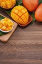 Fresh mango, beautiful chopped fruit with green leaves on dark wooden table background. Tropical fruit design concept. Flat lay. Royalty Free Stock Photo