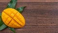 Fresh mango,beautiful chopped fruit with green leaves on dark wooden table background. Tropical fruit design concept. Flat lay. Royalty Free Stock Photo