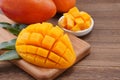 Fresh mango,beautiful chopped fruit with green leaves on dark wooden table background. Tropical fruit design concept. Flat lay.