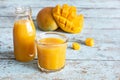 Fresh mango juice in a glass glass with mango slice on a blue wooden background. Exotic drink. Royalty Free Stock Photo