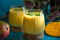 Fresh mango lassi in glasses on blue background with copy space