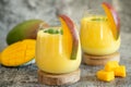 Fresh mango lassi in glasses on grey background with copy space