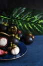 Fresh Mangosteen on Blue Plate with Green Leaf on Background