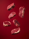 Fresh marbled beef cuts floating against deep red background, showcasing rich textures and colors. Perfect for culinary Royalty Free Stock Photo