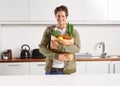 Fresh from the market. A young man in a kitchen holding a brown paper bag filled with vegetables. Royalty Free Stock Photo