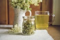 Fresh Meadowsweet, Filipendula ulmaria in jug shape vase and it`s herbal tea in glass, tea powder in jar.