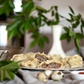 Fresh meat dumplings plate at kitchen table with green plants in vase on blurred background. Convenient food preparation Royalty Free Stock Photo