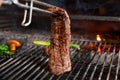 Fresh meat on hot grilled cook with forceps closeup view Royalty Free Stock Photo