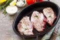 Fresh meat. Marinated raw beef for stakes in the cast-iron grill pan, tomatoes, olive oil, spices and fresh rosemary on a kitchen Royalty Free Stock Photo