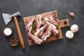 Fresh meat. Raw pork ribs with spices and an ax on a wooden board on a black background. View from above Royalty Free Stock Photo