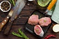 Fresh meat. Raw pork steak on a cast iron frying pan, spices and fresh rosemary on a kitchen wooden table. Royalty Free Stock Photo