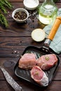 Fresh meat. Raw pork steak on a cast iron frying pan, spices and fresh rosemary on a kitchen wooden table Royalty Free Stock Photo