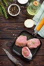 Fresh meat. Raw pork steak on a cast iron frying pan, spices and fresh rosemary on a kitchen wooden table. Flat lay. Royalty Free Stock Photo