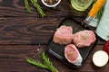 Fresh meat. Raw pork steak on a cast iron frying pan, spices and fresh rosemary on a kitchen wooden table. Royalty Free Stock Photo