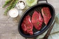 Fresh meat. Raw steak beef on a cast-iron grill frying pan, olive oil, spices and fresh rosemary on the kitchen table. Flat lay. Royalty Free Stock Photo