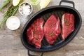Fresh meat. Raw steak beef on a cast-iron grill frying pan, olive oil, spices and fresh rosemary on the kitchen table. Flat lay. Royalty Free Stock Photo