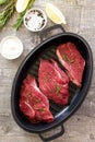 Fresh meat. Raw steak beef on a cast-iron grill frying pan, olive oil, spices and fresh rosemary on the kitchen table. Flat lay. Royalty Free Stock Photo