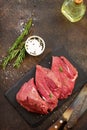 Fresh meat. Raw steak beef on a slate cutting board, olive oil, spices and fresh rosemary on a stone background. Royalty Free Stock Photo