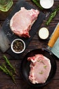 Fresh meat. Raw steak cutlet on a bone on a cast-iron frying pan, olive oil, spices and fresh rosemary on the kitchen table. Flat Royalty Free Stock Photo