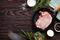 Fresh meat. Raw steak cutlet on a bone on a cast-iron frying pan, olive oil, spices and fresh rosemary on the kitchen table. Royalty Free Stock Photo