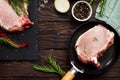 Fresh meat. Raw steak cutlet on a bone on a cast-iron frying pan, olive oil, spices and fresh rosemary on the kitchen table. Royalty Free Stock Photo