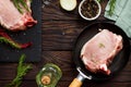 Fresh meat. Raw steak cutlet on a bone on a cast-iron frying pan, olive oil, spices and fresh rosemary on the kitchen table. Flat Royalty Free Stock Photo