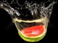 Fresh melon falling in water with splash on black Royalty Free Stock Photo