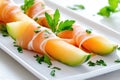 Fresh melon and prosciutto appetizers garnished with basil on a white plate Royalty Free Stock Photo